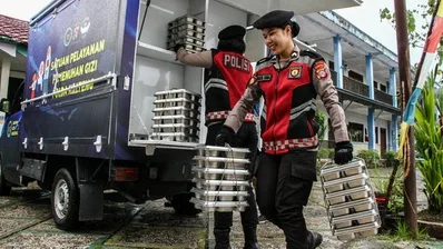 menalar.id,. - Presiden Prabowo Subianto meresmikan 1.179 Satuan Pelayanan Pemenuhan Gizi (SPPG) Polri dan 18 gudang ketahanan pangan Polri di Polsek Palmerah, Jakarta Barat, Jumat (13/2/2026). Mulanya, Prabowo meninjau sejumlah dapur SPPG, kolam bioflok ikan, dan budidaya tanamana hidroponik milik polri. Peresmian 1.179 Dapur MBG Kemudian, Prabowo turut berinteraksi dengan beberapa SPPG Polri di sejumlah daerah. Dalam peresmian tersebut, sejumlah anggota Kabinet Merah Putih hadir, seperti: Menteri Koordinator Pangan Zulkifli Hasan Menteri Koordinator PMK Pratikno Mensesneg Prasetyo Hadi Menteri Kebudayaan Fadli Zon Kepala Badan Gizi Nasional (BGN) Dadan Hindayana Sekretaris Kabinet Teddy Indra Wijaya Kepala Staf Kepresidenan M Qodari, dan Wakil Gubernur DKI Jakarta Rano Karno. Lalu, Kapolri Jenderal Listyo Sigit Prabowo mengungkap pihaknya memiliki target pembangunan SPPG sebanyak 1.500 di seluruh Indonesia pada 2026. Dengan target tersebut, polri kini memiliki peran besar dalam pelaksanaan Makan Bergizi Gratis (MBG). Kemudian, muncul pertanyaan mendasar, bolehkah polri sebagai institusi penegak hukum dapat mengelola SPPG atau dapur umum MBG? Apakah Polri Dapat Mengelola Dapur MBG? Menurut Undang-Undang Pasal 14 Nomor 2 Tahun 2002 polri memiliki tanggung jawab, antara lain: Melaksanakan pengaturan, penjagaan, pengawalan, dan patroli terhadap kegiatan masyarakat dan pemerintah sesuai kebutuhan. Menyelenggarakan segala kegiatan dalam menjamin keamanan, ketertiban, dan kelancaran lalu lintas di jalan. Membina masyarakat untuk meningkatkan partisipasi masyarakat, kesadaran hukum masyarakat serta ketaatan warga masyarakat terhadap hukum dan peraturan perundang-undangan. Turut serta dalam pembinaan hukum nasional. Memelihara ketertiban dan menjamin keamanan umum. Melakukan koordinasi, pengawasan, dan pembinaan teknis terhadap kepolisian khusus, penyidik pegawai negeri sipil, dan bentuk-bentuk pengamanan swakarsa. Melakukan penyelidikan dan penyidikan terhadap semua tindak pidana sesuai dengan hukum acara pidana dan peraturan perundang-undangan lainnya. Menyelenggarakan identifikasi kepolisian, kedokteran kepolisian, laboratorium forensik dan psikologi kepolisian untuk kepentingan tugas kepolisian. Melindungi keselamatan jiwa raga, harta benda, masyarakat, dan lingkungan hidup dari gangguan ketertiban dan/atau bencana termasuk memberikan bantuan dan pertolongan dengan menjunjung tinggi hak asasi manusia. Melayani kepentingan warga masyarakat untuk sementara sebelum ditangani oleh instansi dan/atau pihak yang berwenang. Memberikan pelayanan kepada masyarakat sesuai dengan kepentingannya dalam lingkup tugas kepolisian; sertal. melaksanakan tugas lain sesuai dengan peraturan perundang-undangan. Kemudian, dalam Peraturan Presiden (PP) Pasal 19 ayat (1) Nomor 115 Tahun 2025 tentang Tata Kelola Penyelenggaraan Program MBG menyebut jika BGN dapat bekerja sama denga instansi pemerintah, perseroan terbatas, perseroan perorang, Koperasi, BUM Desa, BUMN, BUMD, atau badan usaha berbadan hukum lainnya. Kemudian juga persekutuan komanditer atau badan usaha tidak berbadan hukum lainnya, usaha mikro, usaha kecil, dan usaha menengah, serta yayasan atau lembaga organisasi atau kemasyarakatan berbadan hukum lainnya. Apabila mengacu pada dua peraturan tersebut, polri tidak melanggar karena hal itu masuk ke dalam pelayanan kepada masyarakat dan mendukung program pemerintah. Meski demikian, hal ini mengkhawatirkan sebab proses pemantauannya sulit dan tertutup. Respons Pakar Direktur Eksekutif Centre for Indonesia Strategic Actions (CISA) Herry Mendrofa turut merespons kekhawatiran tersebut, Ia menjelaskan secara normatif, selain sebagai intervensi gizi, program MBG juga mendorong partisipasi UMKM, koperasi, dan kelompok masyarakat desa. "Ketika aktor politik lokal menjadi pelaksana langsung, terjadi deviasi fungsi yang mana dari pengawasan menjadi eksekusi. Ini bertentangan dengan prinsip separation of roles dalam tata kelola publik," tegasnya, Selasa (16/9/2025) melansir dari Inilah.com. Ia menilai apabila ada dominasi dari instansi hukum dan elite politik semacam ini, maka berisiko menciptakan rent-seeking behavior. Maksudnya, keputusan alokasi tidak lagi berbasis efisiensi atau keadilan, melainkan kepentingan pribadi atau kelompok. "Akibatnya dapat menghambat inklusi UMKM dan melemahkan efek ekonomi berganda, yang seharusnya dihasilkan oleh program MBG," pungkas Herry. Konflik Dapur MBG Milik Polri Sebelumnya, sejumlah masyarakat melaporkan jika polri melakukan "pencaplokan" kuota ke sekolah-sekolah yang sudah bekerja sama dengan dapur MBG yang masyarakat kelola. Dapur MBG yang masyarakat kelola beralasan pihaknya harus mencari sekolah lain dengan jarak tempuh lebih jauh. Menanggapi hal tersebut, Wakil Ketua Komisi IX DPR RI Yahya Zaini membenarkan hal tersebut. "Jadi SPPG yang sudah kerja sama dengan sekolah, ini disuruh pindah oleh polisi. Ini banyak kasus-kasus ini, Pak. Ini yang melaporkan ke saya itu di Grobogan dan Brebes," ucap Yahya. Beberapa hari kemudian, Yahya memberi klarifikasi sekaligus menyampaikan permintaan maaf kepada pihak Polri. Ia menilai, sikap Polri tak bukan karena kondisi dapur MBG Polri jauh lebih layak dan dapat menjadi contoh. "Pernyataan saya di rapat Komisi IX pada RDP bersama BGN sebelumnya saya luruskan. Saya memohon maaf kepada polri atas kekeliruan tersebut. SPPG Polri terbukti memiliki standar yang back dan menjadi mitra yang dapat diandalkan," Sambungnya. Yahya memuji dapur MBG Polri yang memiliki standar baik, mulai dari bangunan permanen, peralatan dapur lengkap, hingga kendaraan distribusi sendiri.